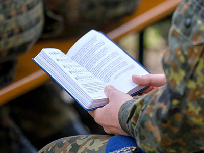 Soldat hält ein Gesangbuch in der Hand. Foto: (c) epd-Bild, Jens Schulze