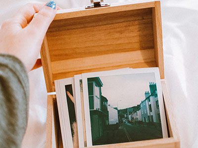 Eine junge Frau stöbert in einer Kiste mit Erinnerungsfotos. (c) Foto: Pexels