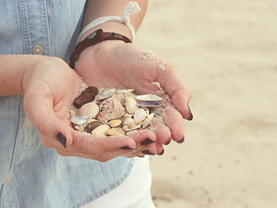 Junge Frau sammelt Muscheln am Strand. (c) Foto: Pixabay