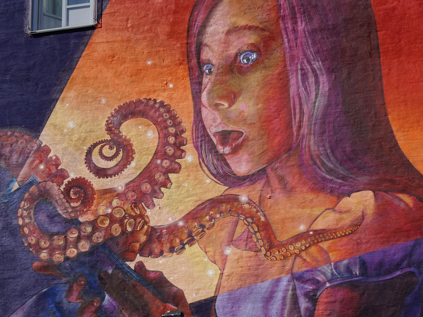 Graffiti auf einer Wand. Ein Mädchen bestaunt einen Oktopus. (c) Pixabay