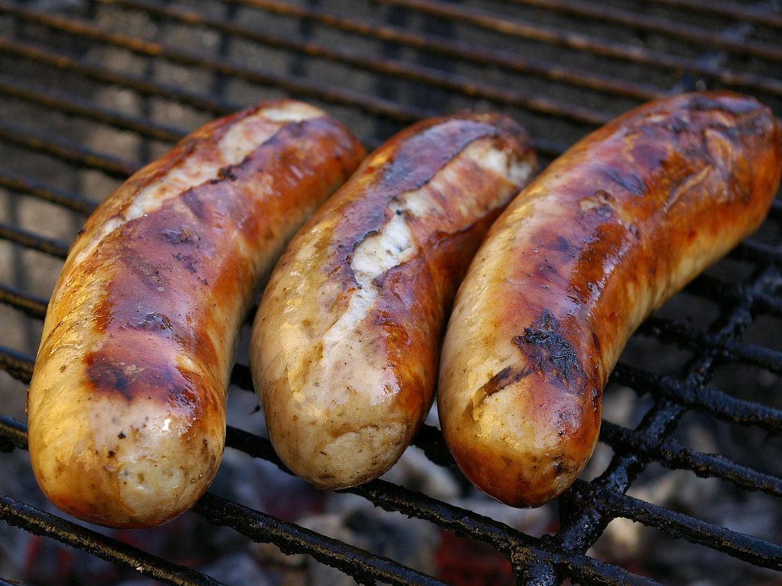 Drei Bratwürstchen liegen goldbraun auf einem Grill. (c) Foto: Pixabay