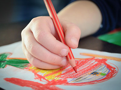 Ein Kind malt mit Buntstiften ein Bild. (c) Foto: Pixabay