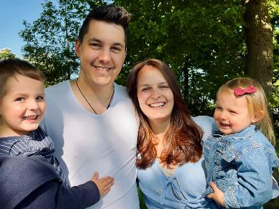 eine junge Familie mit zwei kleinen Kindern auf dem Arm