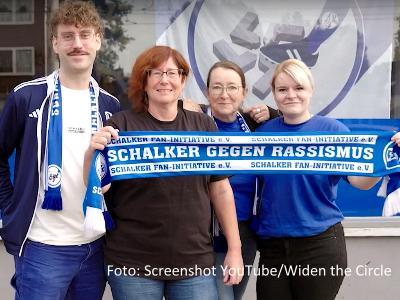 vier Fans von Schalke 04 posieren mit dem Vereinsschal vor der Kamera