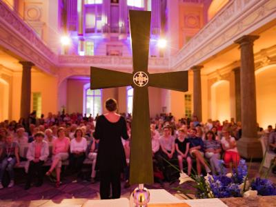 im Vordergrund ein großes Kreuz, dahinter versammelte Gemeinde
